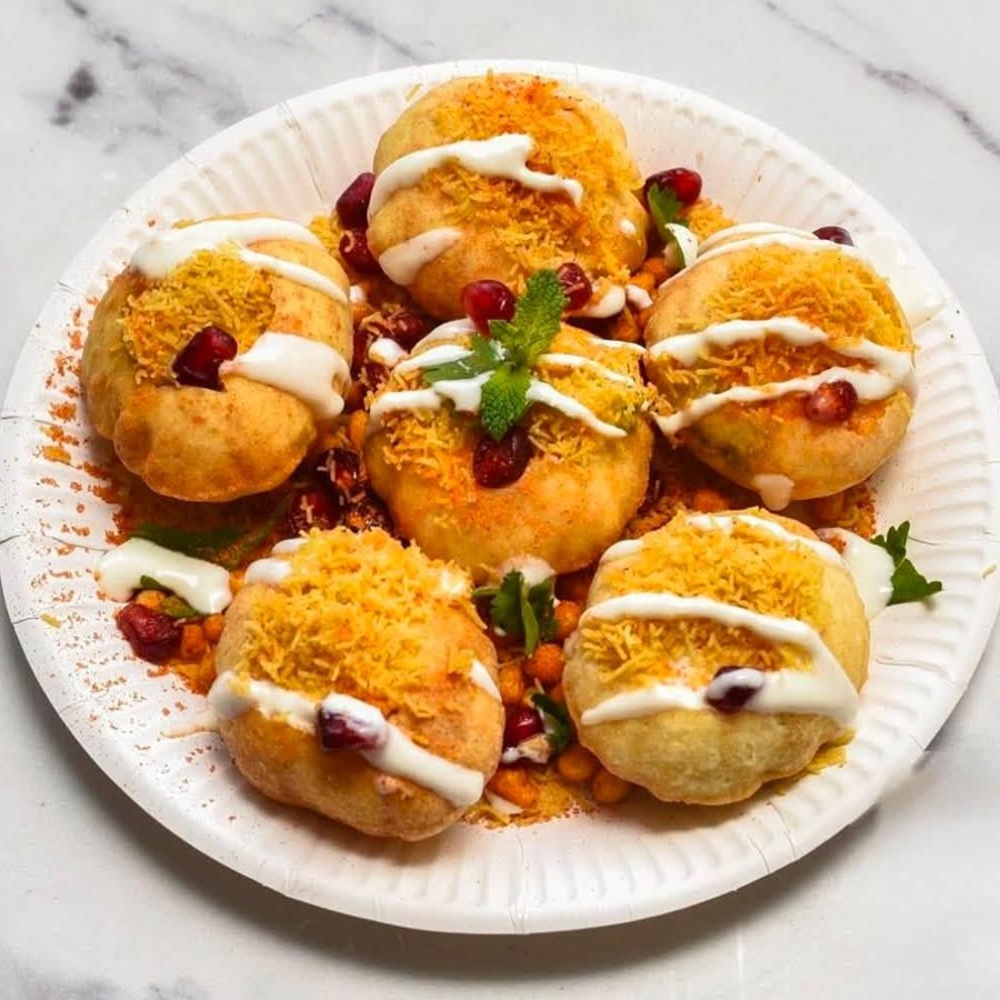 Puris topped with sev, yogurt and pomegranate